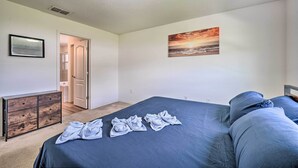 Un dormitorio con cama, cómoda, un cuadro y una puerta que da a otra habitación.