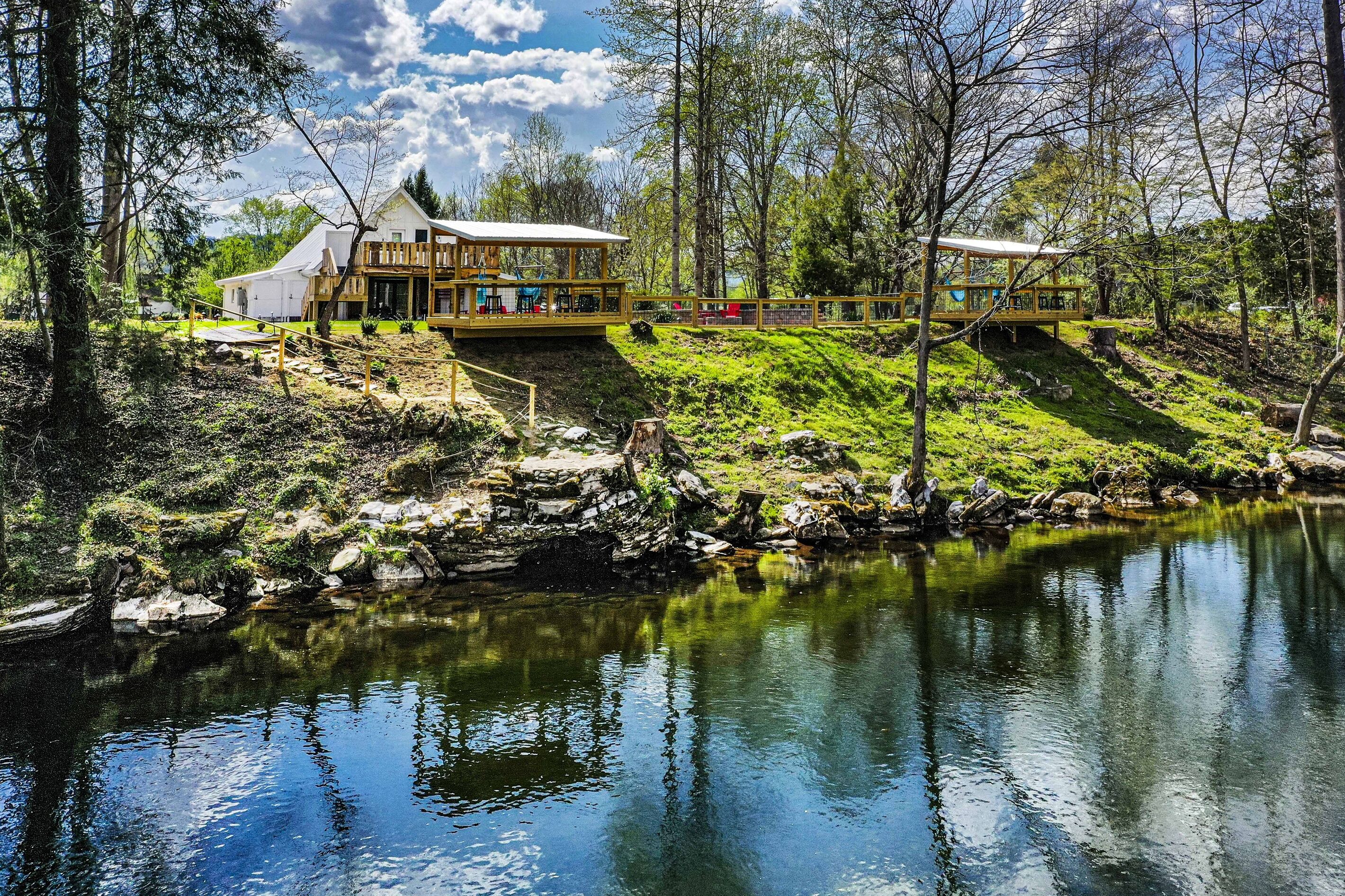 A lakeside property with a main building and a wooden deck.