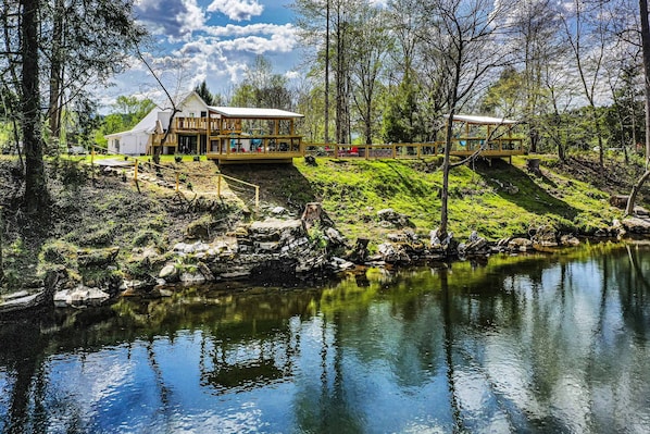A lakeside property with a main building and a wooden deck. - Riverfront farmhouse. Walking distance to awesome! (Townsend)