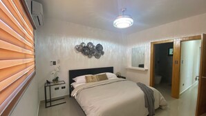 Een slaapkamer met een bed, nachtkastje, wanddecoratie en een plafondventilator.