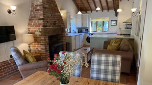 Una sala de estar acogedora con chimenea, una mesa de comedor y una cocina al fondo.