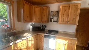 Una cocina con armarios de madera, un lavamanos de acero inoxidable, una estufa y un refrigerador.