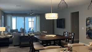 Een moderne woonkamer met een eethoek, houten meubels en hanglampen.
