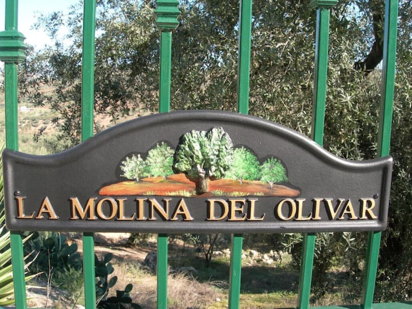 Een bord met de tekst 'LA MOLINA DEL OLIVAR' en een afbeelding van bomen en landschap.