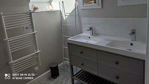Une salle de bain moderne avec un puits de lumière, un meuble-lavabo blanc, un miroir et un porte-serviettes.