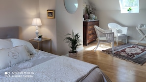 Une chambre à coucher comprenant un lit, une table de chevet, une lampe, une commode, une chaise et une fenêtre.