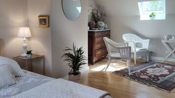 Een slaapkamer met een bed, nachtkastje, lamp, dressoir, stoel en een raam.