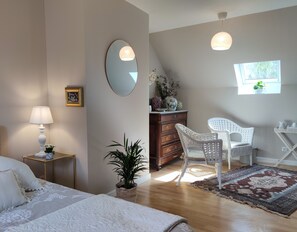 Un dormitorio con cama, mesita de noche, lámpara, cómoda, silla y ventana.