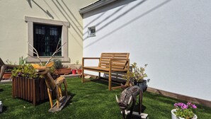 Un banco de madera, una mesita y plantas en macetas en un jardín bien cuidado.