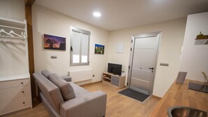 Una sala de estar moderna con un sofá gris, una televisión y suelo de madera.