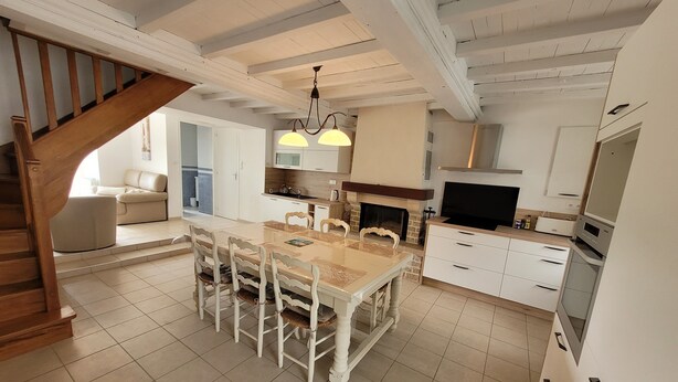 Een ruime keuken met een eethoek, een open haard en een trap naar een andere kamer.