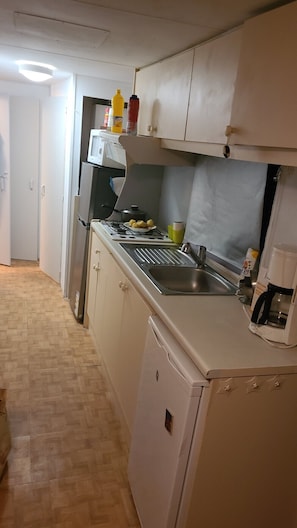 A compact kitchen with a microwave, stove, sink, and cabinets. - Mobile home (Mimizan)
