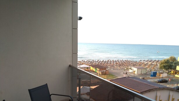 A balcony with two chairs, a small table with fruit and a pineapple, and a view of the beach and umbrellas. - 2 apartments, of 2 rooms each, next each other, for max 10 persons, beachfront (Navodari)