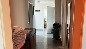 Un couloir étroit avec un plancher en bois, un ventilateur de plafond et un coin cuisine équipé de placards et d’un évier.