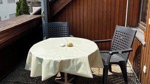 Une table ronde recouverte d’une nappe blanche, deux chaises et un petit fruit posé sur la table.