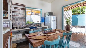 Una cocina compacta con una mesa de madera, sillas azules y un refrigerador.