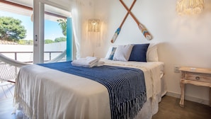Un dormitorio con cama, una hamaca, una mesita de noche de madera y una lámpara fijada en la pared.
