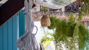 Una maceta colgante con plantas, una bolsa de plástico blanca y una estructura de madera con un muro azul de fondo.