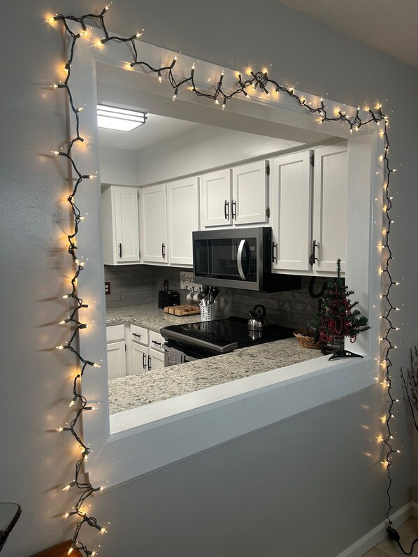 A kitchen with white cabinets, a microwave, and a small Christmas tree.