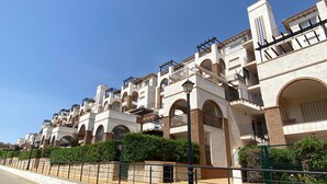 A row of modern multi-story buildings with balconies and arched windows.