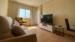 A living room with a sofa, a television, a small table, and a chair.