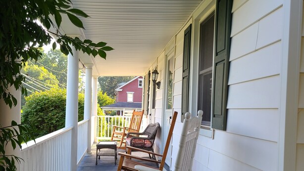 A porch with rocking chairs and a wooden deck.