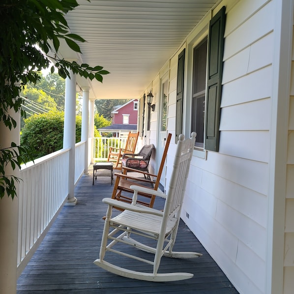 A porch with rocking chairs and a wooden deck.