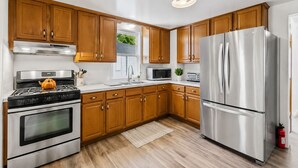A modern kitchen with wooden cabinets, stainless steel appliances, and a large refrigerator.