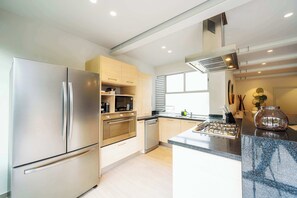 A modern kitchen with stainless steel appliances, wooden cabinets, and a central island. - Capitalia | Exclusive Zen Oasis near Lincoln Park (Ciudad de México)