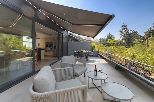 A modern outdoor patio with seating, a table, and a bottle of wine.