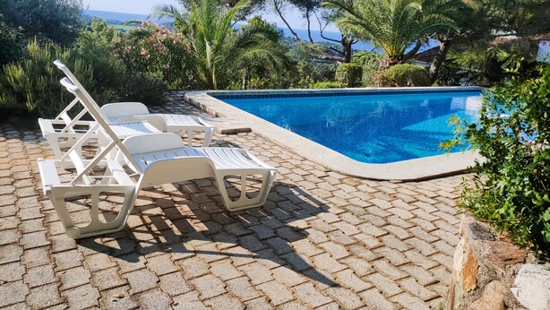 A swimming pool with lounge chairs and a view of the sea.