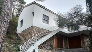 A house with a stone exterior, a white staircase, and a garage.