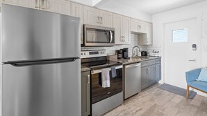 A modern kitchen with stainless steel appliances, light wood cabinets, and a built-in oven. - Deluxe King Suite w/Deck (Saint James City)