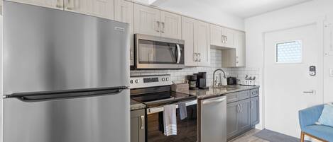 A modern kitchen with stainless steel appliances, light wood cabinets, and a built-in oven.