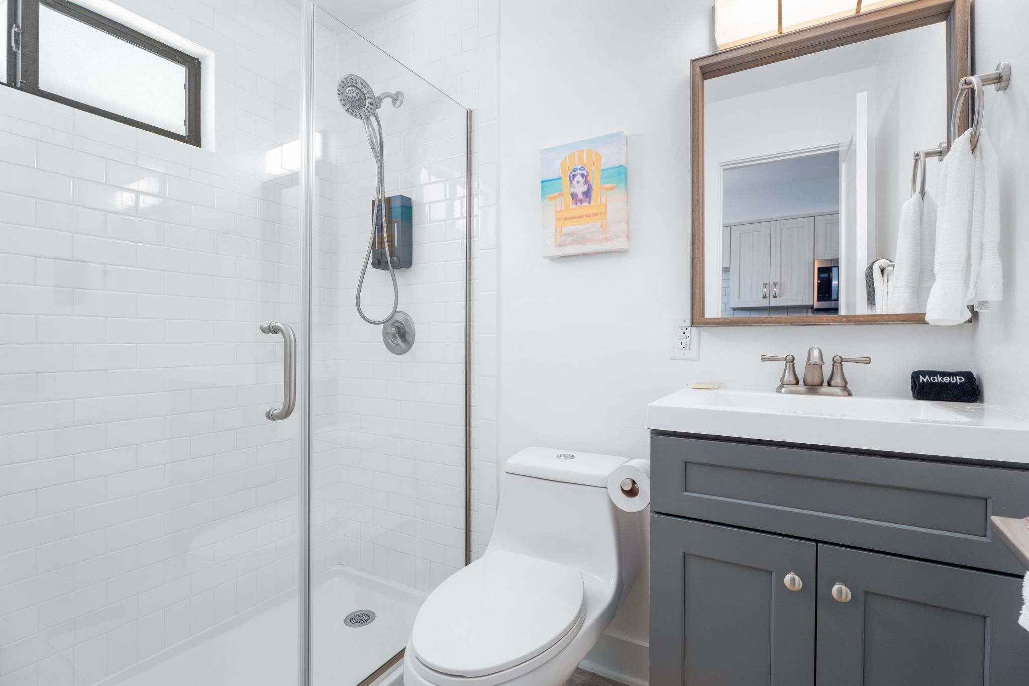 A modern bathroom with a glass-enclosed shower, a white toilet, and a vanity with a mirror.