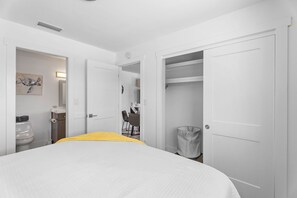 A hotel room with a bed, a bathroom, a desk, and a closet.