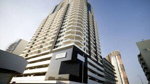 A high-rise building with multiple balconies, a sign indicating 'Mata', and a modern architectural design.