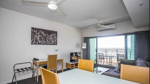 A hotel room with a balcony, a dining area, a sofa, and a ceiling fan.