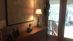 A room with a large map on the wall, a lamp on a wooden console table, and a view of the outdoors through a sliding door. - Lake front beauty (Hillman)