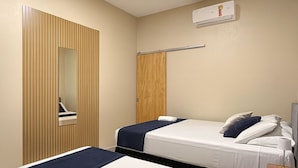 Habitación de hotel con dos camas, un espejo, un armario y un equipo de aire acondicionado.