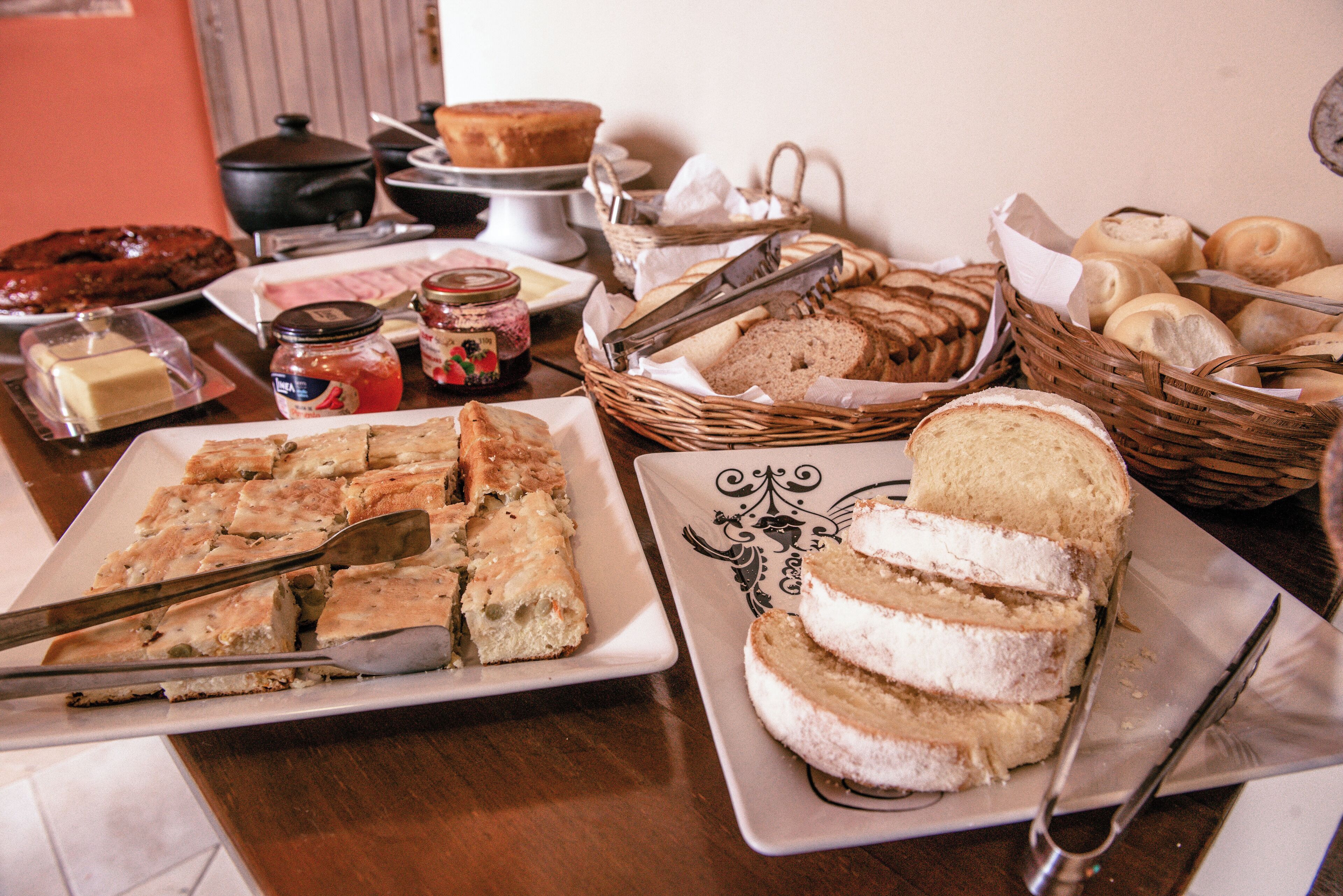 A table with various food items including bread, pastries, and a cake.