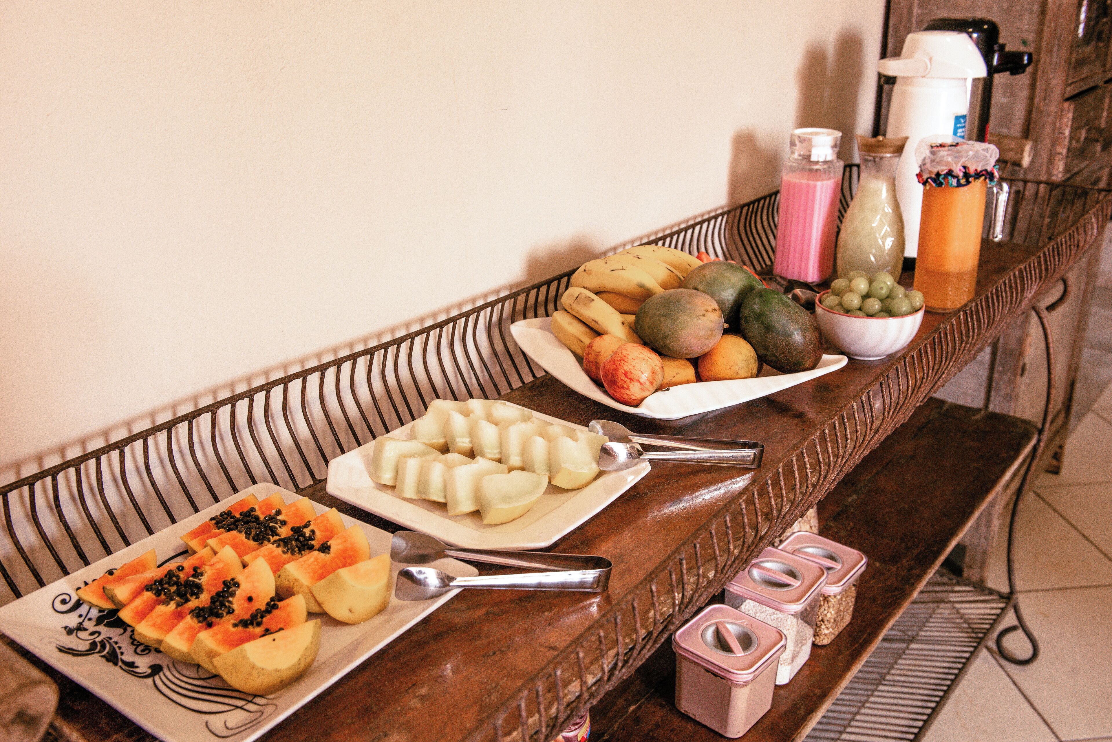 A buffet table with various fruits, vegetables, and beverages.