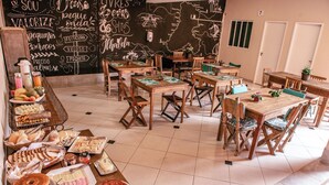 Un comedor con varias mesas y sillas, un bufé con diversas opciones de comida y una pared de pizarra con escritura decorativa.