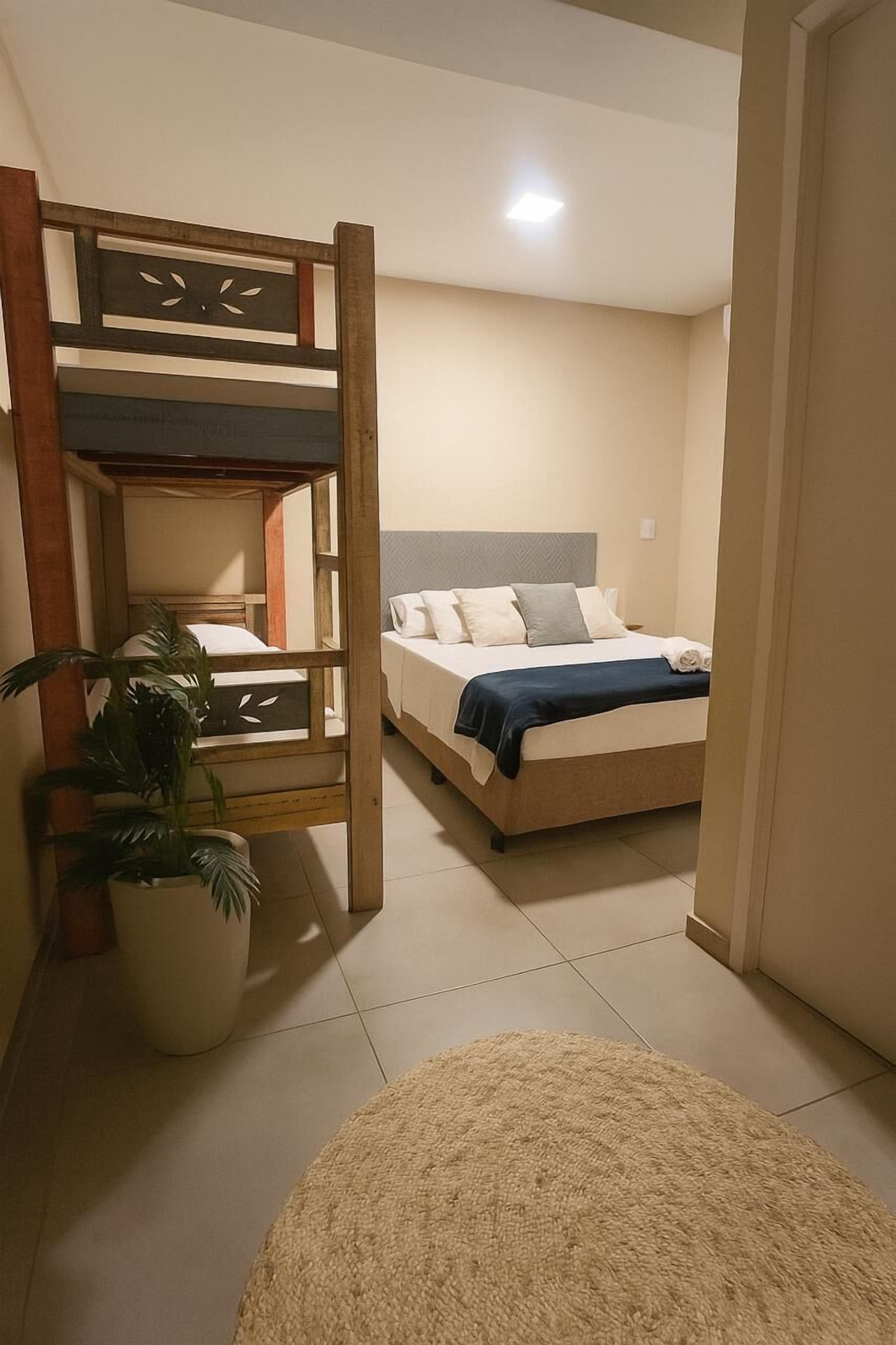 A room with a bunk bed, a potted plant, and a round rug.