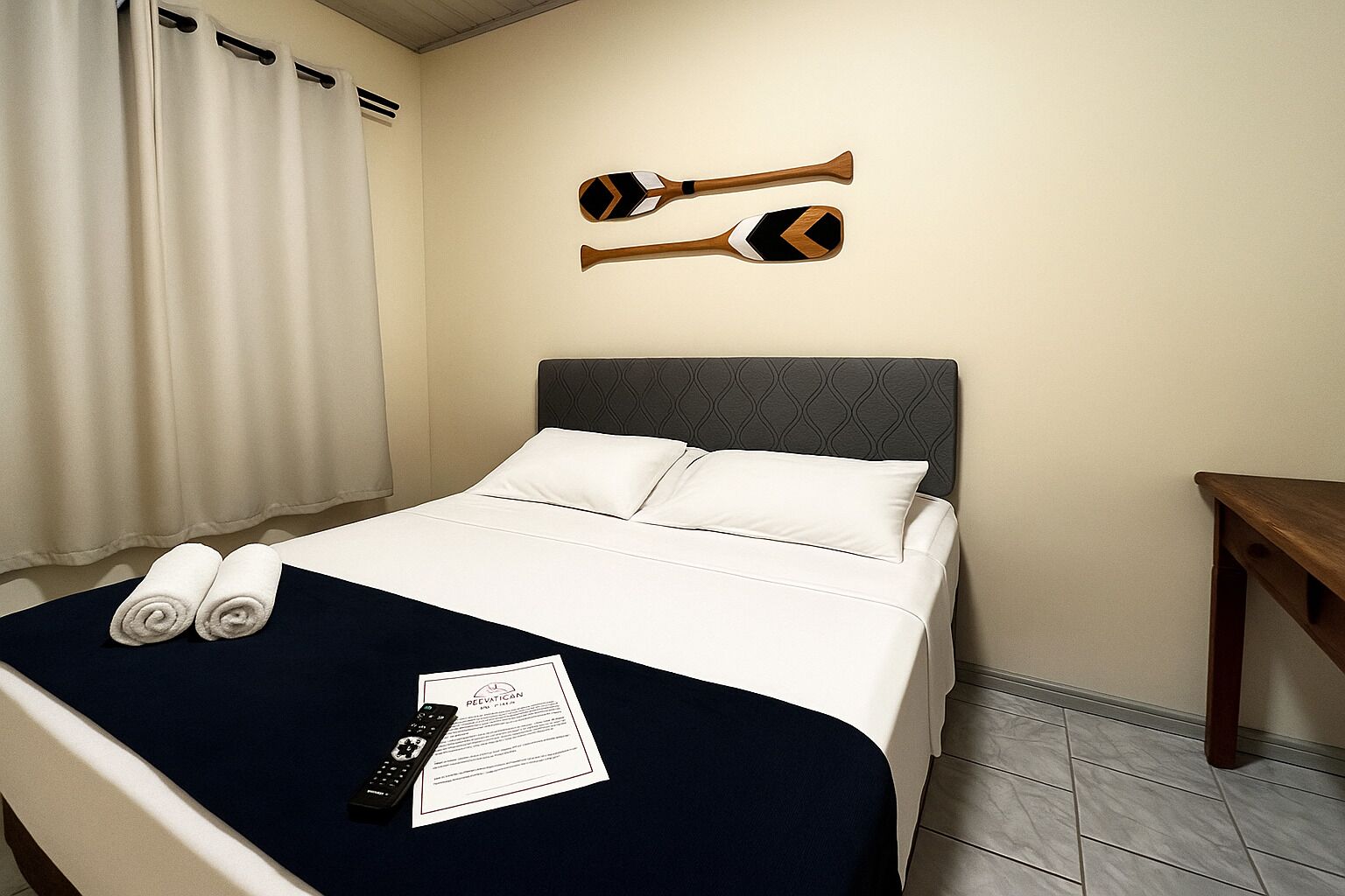 A hotel room with a bed, pillows, a remote control, and a document on the bed.