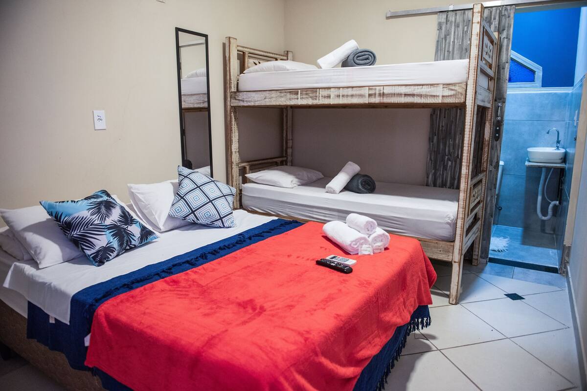 A bunk bed room with a red blanket, a remote control, and towels on the bed.