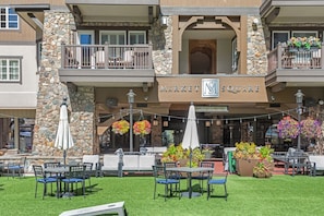 A building with a stone facade, outdoor seating area with tables and chairs, and hanging flower baskets. - Charlie Rentz: Luxury Ski-In/Out, BC Village, Sleeps 8, 3 King Beds, AC, Walk to Everything (Beaver Creek)