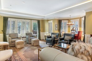 A spacious living room with a large window, a fireplace, and a chandelier. - Charlie Rentz: Luxury Ski-In/Out, BC Village, Sleeps 8, 3 King Beds, AC, Walk to Everything (Beaver Creek)