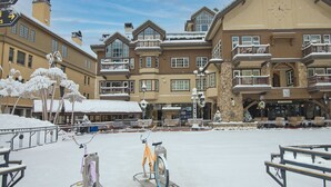 A snow-covered plaza with a bicycle rental station, a Market Square building, and a snow-covered tree. - Charlie's Slopeside: Luxury Ski-In/Out, BC Village, Sleeps 8, 3 King Beds, AC, Walk to Everything (Beaver Creek)