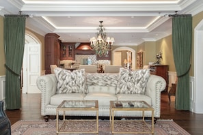 A spacious living room with a beige sofa, two matching armchairs, a glass coffee table, and a chandelier. - Charlie Rentz: Luxury Ski-In/Out, BC Village, Sleeps 8, 3 King Beds, AC, Walk to Everything (Beaver Creek)